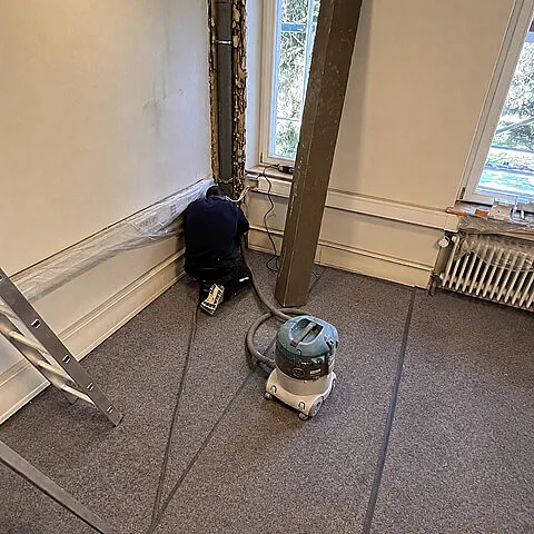 Innenraum während der Bauarbeiten mit geöffneter Wand und laufenden Installationsarbeiten