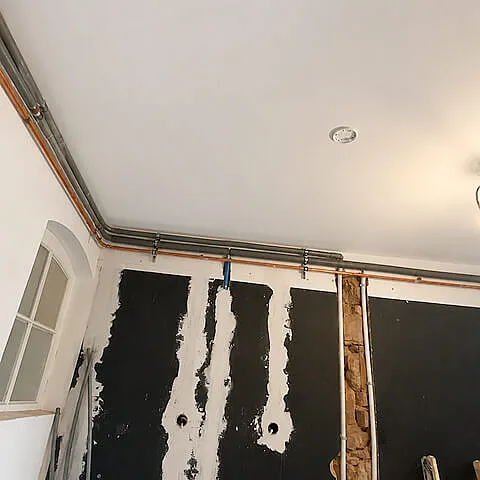 Vorbereiteter Raum mit Deckenleitungen und Wandflächen für den weiteren Innenausbau in Freiburg