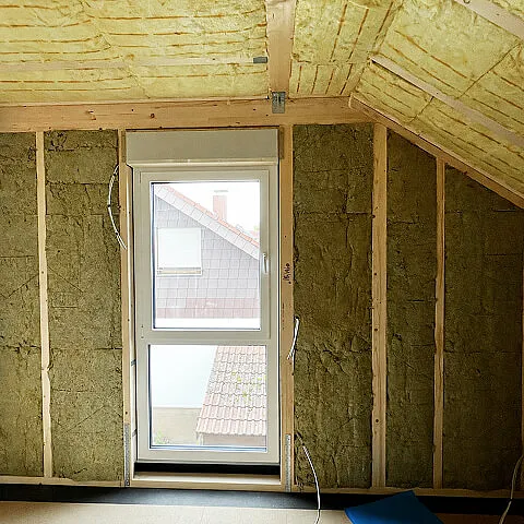Gedämmte Dachgeschosswand mit Fenster und sichtbarer Holzunterkonstruktion im Massahaus Gebäude