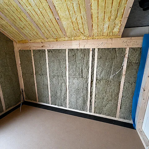Mineralwolldämmung zwischen Holzständern im Innenbereich eines Dachgeschosses