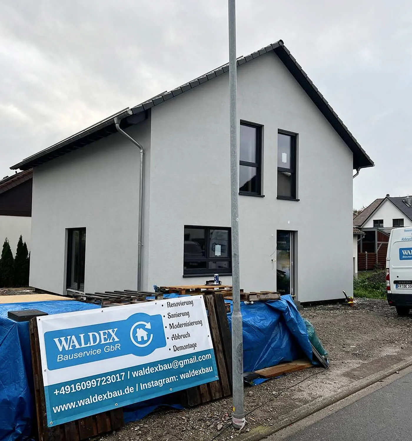 Modernes zweigeschossiges Massahaus Gebäude mit fertiggestellter Fassade und Baustellensituation im Vordergrund